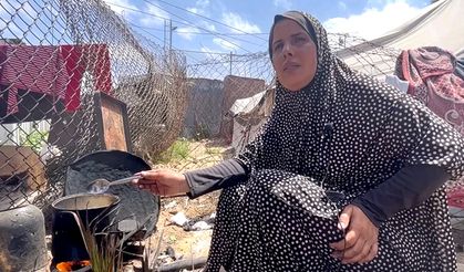 Filistinli kadın çocuklarına yemek pişirebilmek için yakacak olarak çöpleri kullanıyor