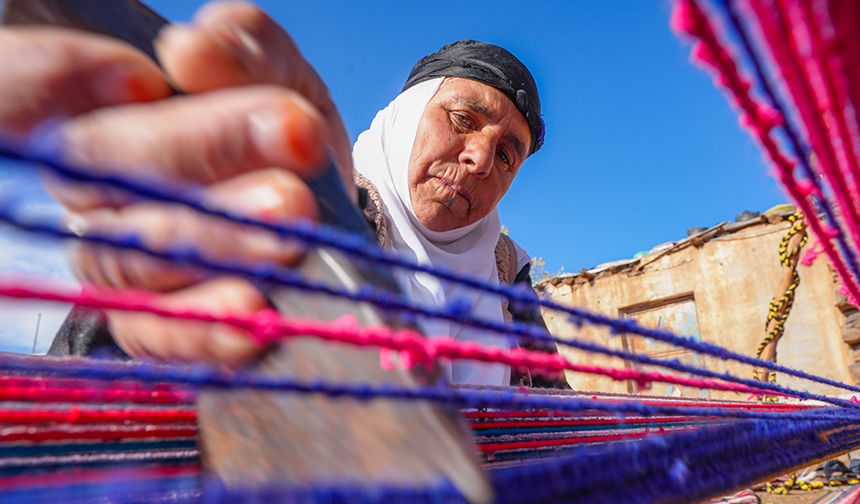 Evinin bahçesindeki tezgahta asırlık yöntemle kilim dokuyor